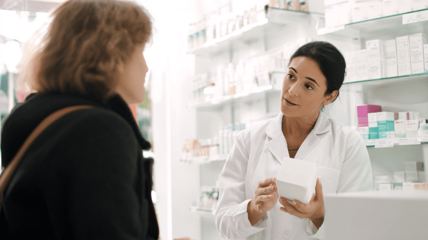 Farmaceutka udzielająca porady pacjentowi w nowoczesnej placówce, ilustrująca koncept apteka zdrowa i bezpieczne stosowanie leków.