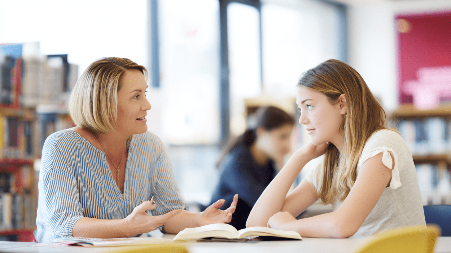Nauczycielka rozmawiająca z uczniem w klasie, ilustrująca praktyczne wykorzystanie wiedzy, którą dają psychologia i studia podyplomowe dla nauczycieli.