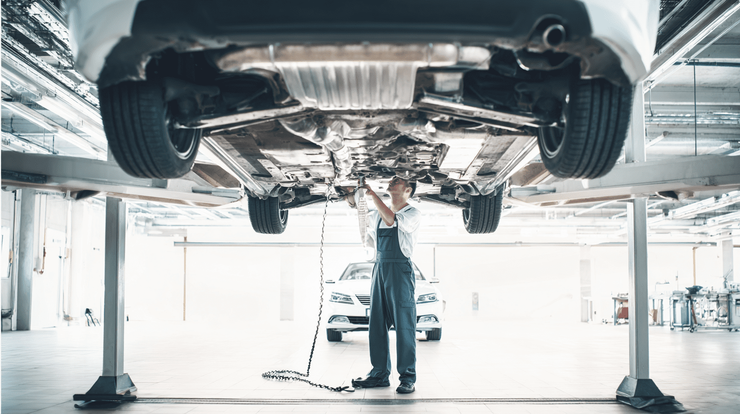 Mechanik w nowoczesnym warsztacie ogląda podwozie auta, sprawdzając stan automatycznej skrzyni biegów i sprzęgła.