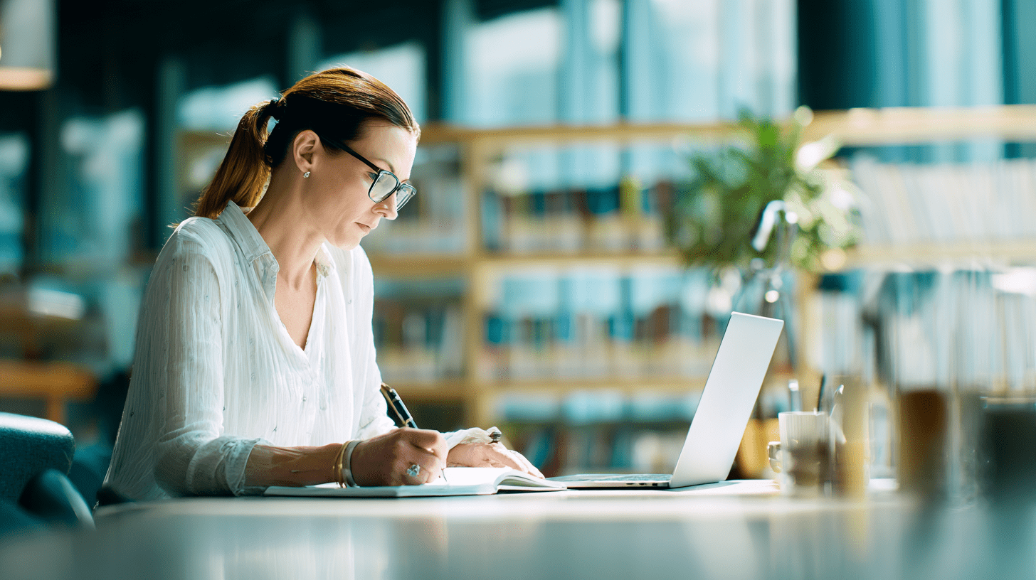 Kobieta w stroju business casual ucząca się przy laptopie, realizująca program studiów podyplomowych zarządzanie zasobami ludzkimi.